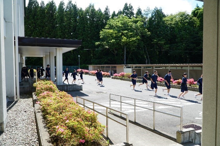 避難訓練の写真。生徒が校舎からグランドへ避難している。