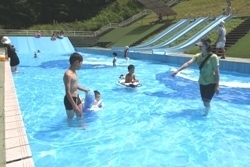 浅くきれいなプールで水着姿の子どもたちが遊んでいます