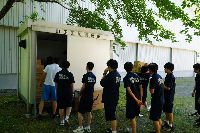 災害時に山田高校が避難所になった場合を想定した常設訓練の写真。生徒が山田町防災倉庫から物品の搬入をしている。