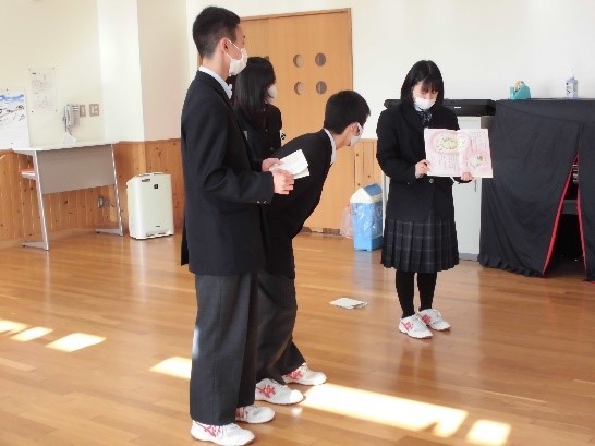 山田高校の保健委員が船越小学校生徒に歯磨き指導を行っている写真。六歳臼歯を題材にした絵本の読み聞かせを行っている。